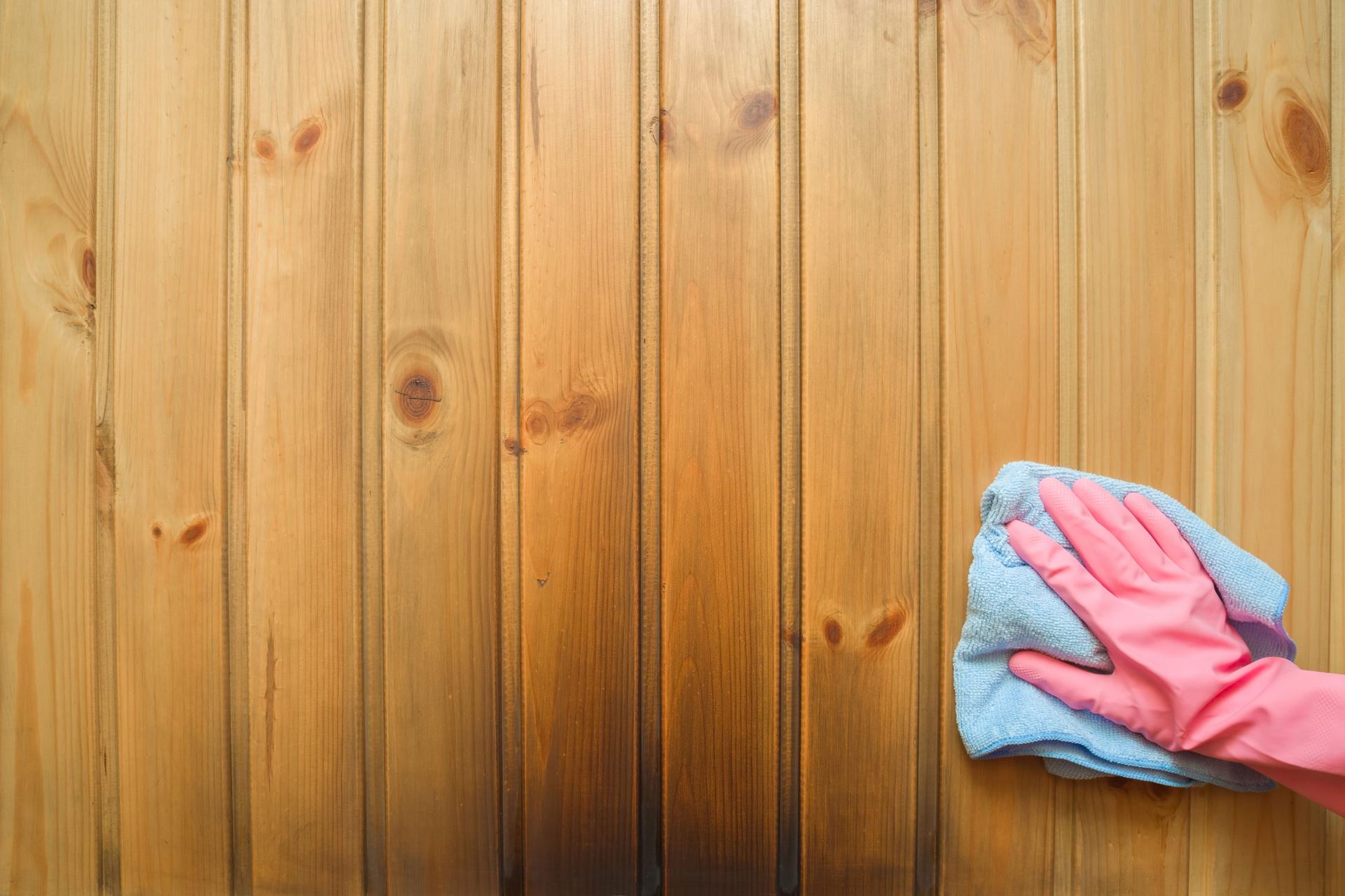 Employee hand in rubber protective glove with rag washing the black soot marks from smoke of furnace on wooden wall. Spring general or regular cleanup. Commercial cleaning company. Service concept.